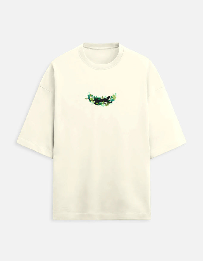 Cream oversized t-shirt with small green forest graphic on chest, minimalist style