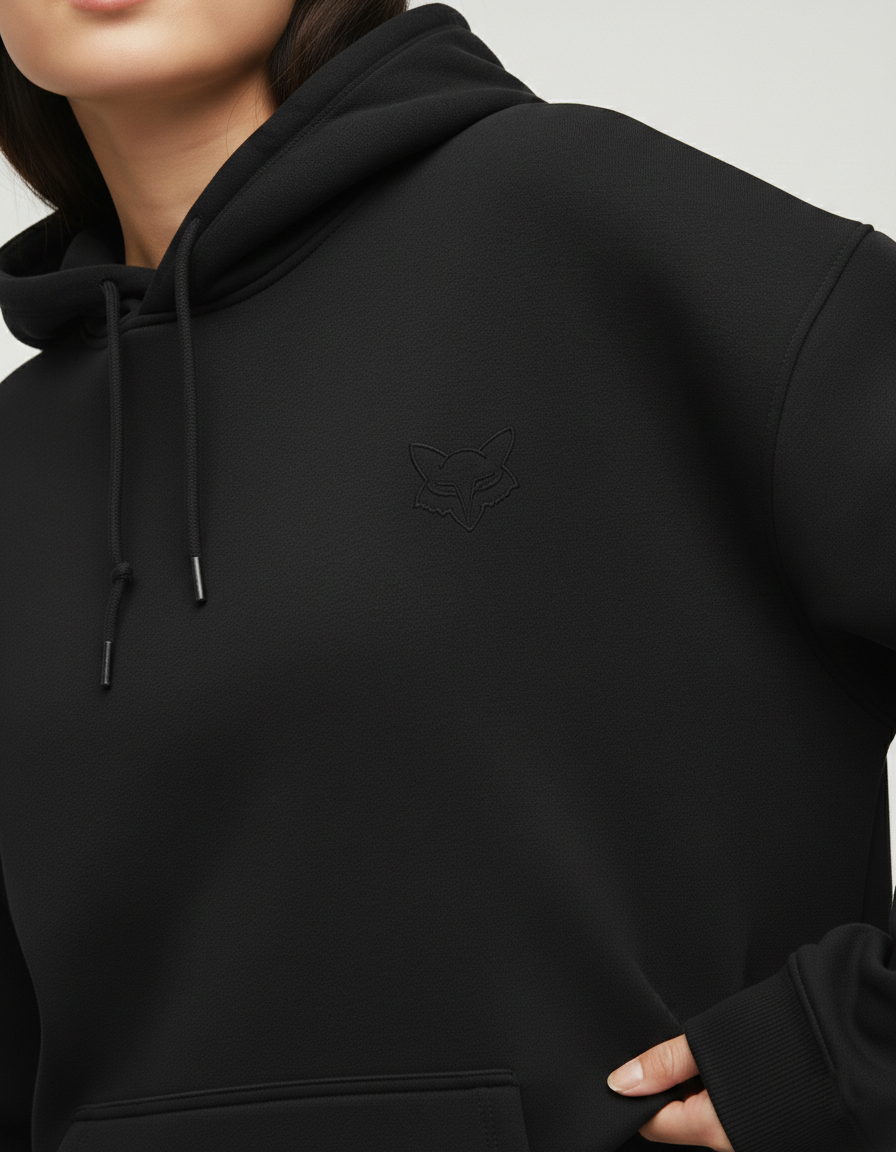 Woman wearing oversized black hoodie with fox logo, drawstrings, and kangaroo pocket