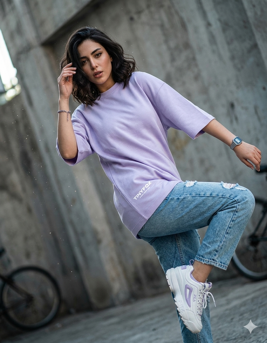 Woman in pastel purple oversized T-shirt and ripped jeans posing outdoors, street style fashion