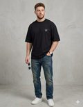 Man in casual black t-shirt with small fox logo, blue jeans, and white sneakers
