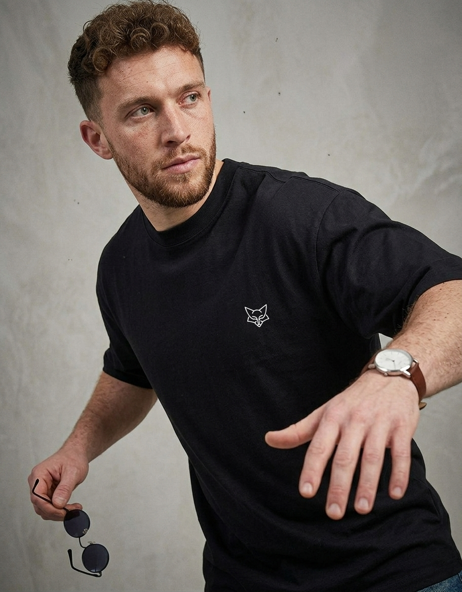 Man wearing black t-shirt with minimalist fox logo on chest, holding sunglasses, casual style