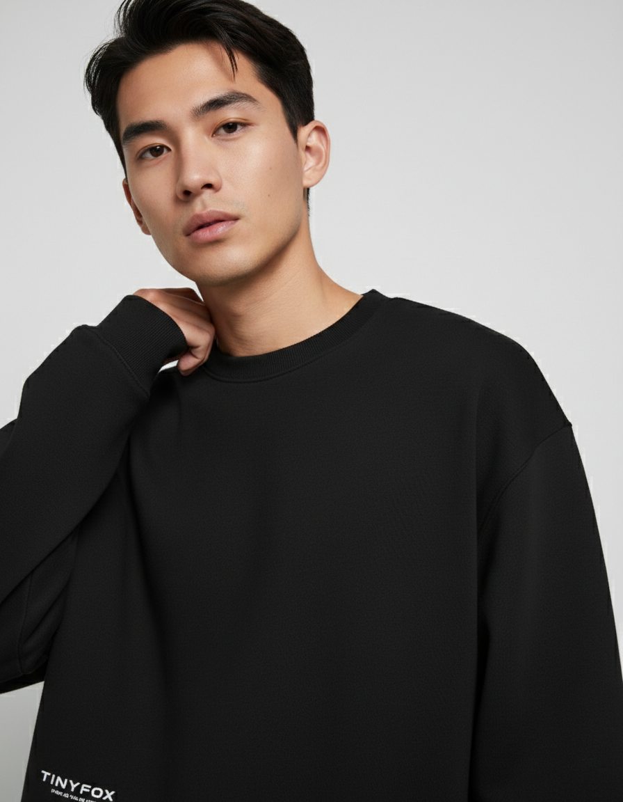 Man wearing black oversized sweatshirt with Tinyfox logo, minimalist studio background