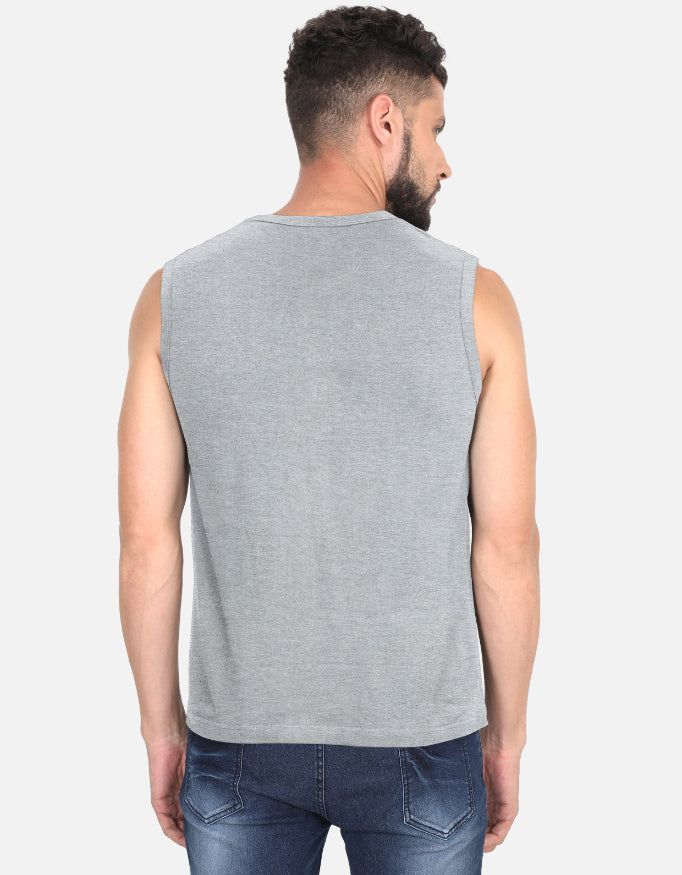 Man wearing a gray sleeveless shirt and blue jeans on a white background